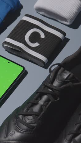 Vertical-Video-Studio-Flat-Lay-Shot-Of-Football-Soccer-Boots-Shirt-Captains-Armband-And-Mobile-Phone-3